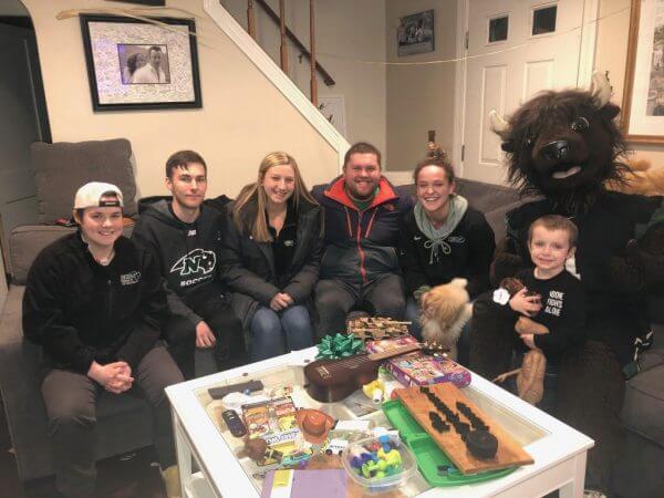 Nichols students sitting on a couch with Quinn Waters and Nichols College's bison mascot, Thunder.